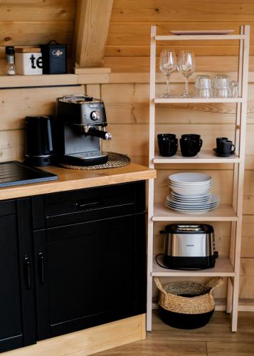 a kitchen with black appliances and plates and wine glasses at Osada Poli Koniaków - Panoramiczny Domek nr 3 z Prywatną Balią i Hydromasażem in Koniaków