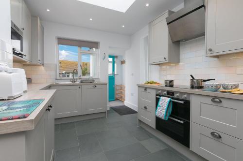 uma cozinha com armários brancos e um forno de fogão preto em Opechee em St. Ives