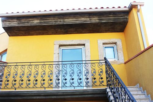 a yellow building with a balcony and two windows at Curral de l Tiu Pino in Sendim