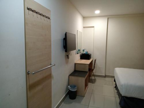 a room with a bed and a television and a door at AVENUE BANGI HOTEL in Kajang