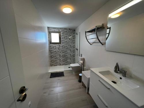 a white bathroom with a sink and a toilet at Arrecife exclusive beach house in Arrecife