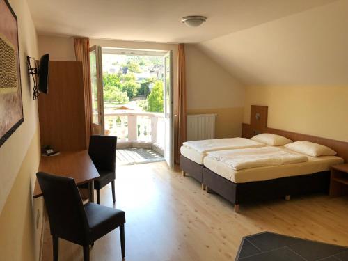 a bedroom with a bed and a desk and a window at Hotel & Restaurant Brühler Hof in Wintrich