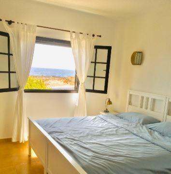 a bedroom with a bed and a large window at PERLE DES MEERES in Charco del Palo