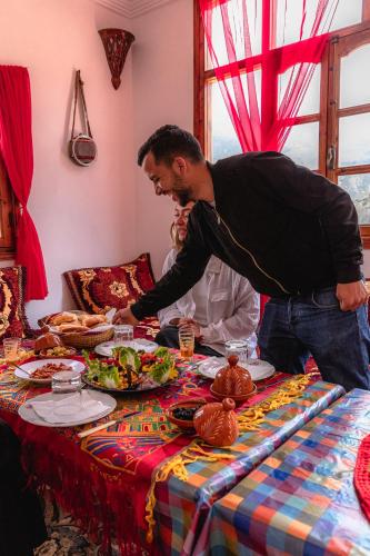 a man standing at a table with a plate of food at Amazigh Family Riad in Imlil