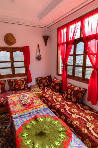 a living room with two beds and red curtains at Amazigh Family Riad in Imlil
