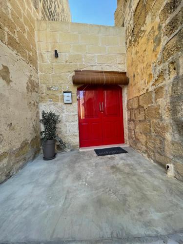 een rode deur in een stenen gebouw met een stenen muur bij Taz-Zubi Farmhouse in San Katald