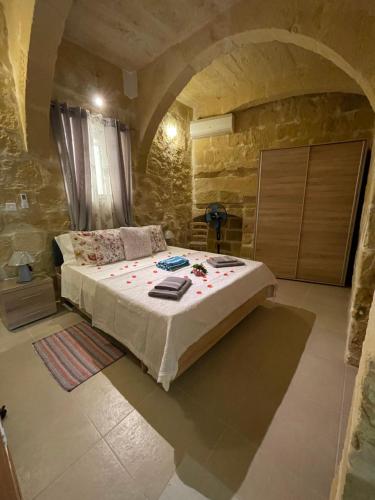 een slaapkamer met een bed in een stenen kamer bij Taz-Zubi Farmhouse in San Katald