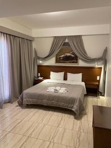 um quarto com uma cama grande e uma janela grande em Aristotelis em Ancient Epidavros