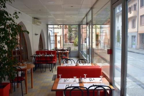 un restaurant avec des tables, des chaises et des fenêtres en verre dans l'établissement Hôtel de l'Europe, à Saint-Jean-de-Maurienne