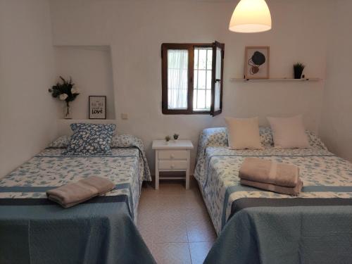 1 dormitorio con 2 camas y ventana en Casa de campo con maravillosas vistas, bbq y piscina, en Ronda