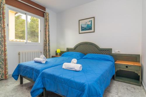 a bedroom with two blue beds with towels on them at Casa Miriam in Cala Ratjada