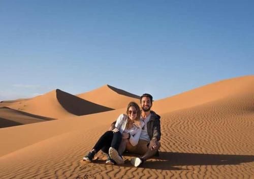 a man and a woman sitting in the desert at Mhamid polski desert camp in El Gouera