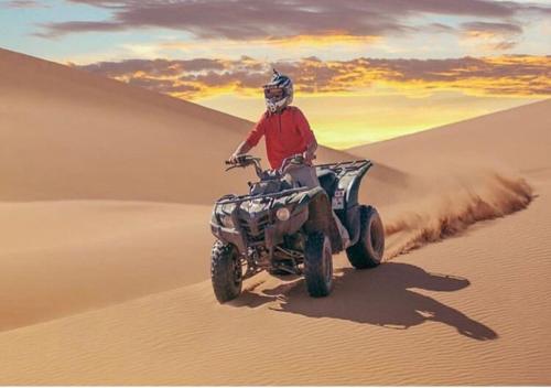 a man riding a quad bike in the desert at Mhamid polski desert camp in El Gouera