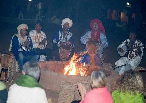 a group of people sitting around a fire at Mhamid polski desert camp in El Gouera
