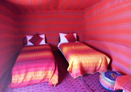 a room with two beds in a striped room at Mhamid polski desert camp in El Gouera