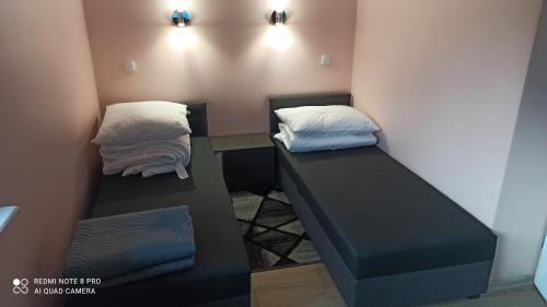 two beds in a room with a desk and two pillows at Pokoje Gościnne Wiki & Ola in Mrzeżyno