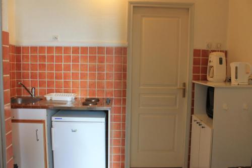 - une cuisine avec un réfrigérateur blanc et du carrelage rouge dans l'établissement Face aux Thermes, à Rochefort