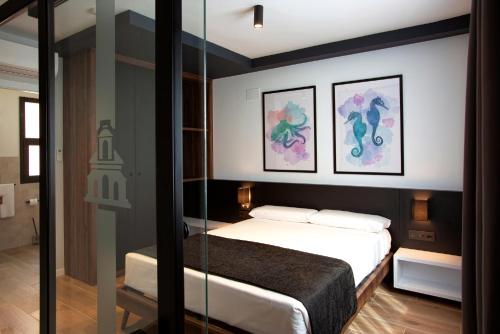 una camera da letto con un letto e due dipinti alle pareti di Apartamentos La Espadaña a Rota