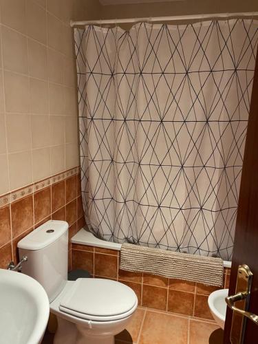 a bathroom with a toilet and a shower curtain at Alojamiento EL BUTAKA in Cala