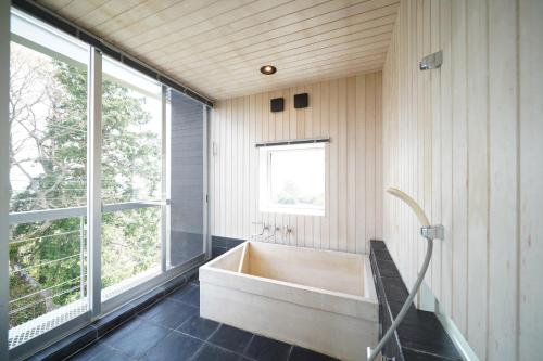 a bathroom with a tub and a window at ファミーユ大室Ⅱ in Futo
