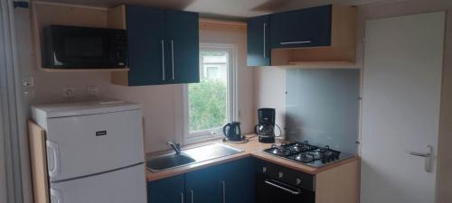 una pequeña cocina con armarios azules y fregadero en Camping les salins de la gardiole, mobile home 6 personnes en Vic-la-Gardiole