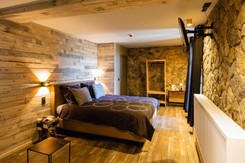 a bedroom with a stone wall and a bed at Le Lignely in Durbuy