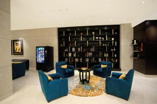 a lobby with blue chairs and a table and a television at Somerset Greenways Chennai in Chennai