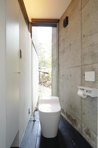 a bathroom with a white toilet and a window at ファミーユ大室Ⅱ in Futo