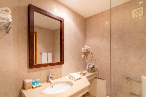 a bathroom with a sink and a shower with a mirror at Hotel da Aldeia - Adults Only in Albufeira