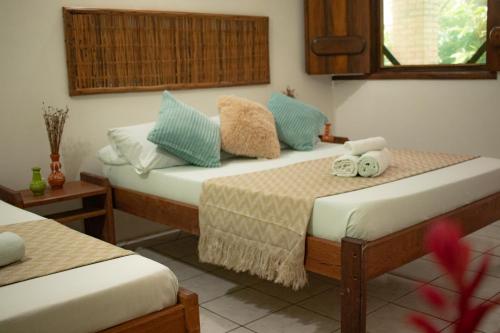 a room with two beds with blue pillows at Pousada Lanai in Itacaré