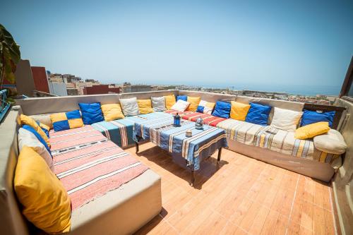 a balcony with couches and a table with pillows at Original Surf Morocco in Tamraght Ouzdar