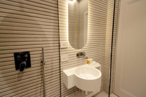 a white bathroom with a sink and a shower at The Crown Boutique Hotel & SPA in Tirana