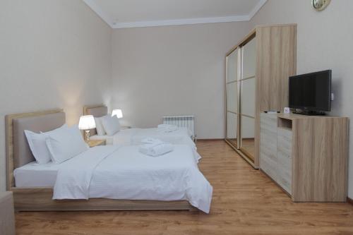 a bedroom with a white bed and a television at HUMSON BULOQ SANATORIUM in Khumson