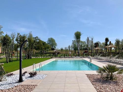 a swimming pool in a park with chairs and trees at Agriturismo Nonno Mario in Fossone dʼAdige