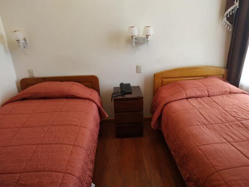 Dormitorio con 2 camas y mesita de noche con teléfono en Hostal Terrabella SRL, en La Paz
