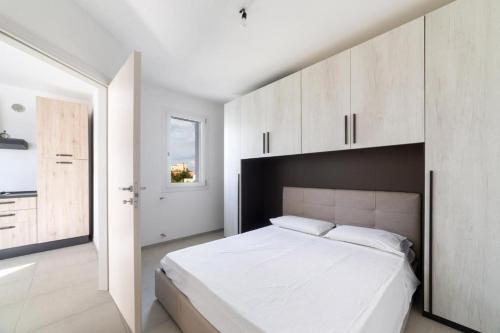 a white bedroom with a large white bed and white cabinets at Quintino Apartments Pool in Torre Lapillo