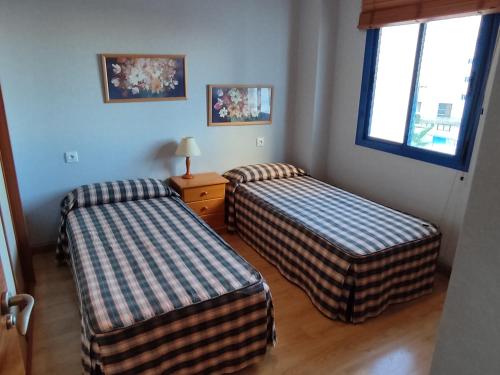 two beds in a room with two windows at Calle Ancla Isla Cristina in Isla Cristina