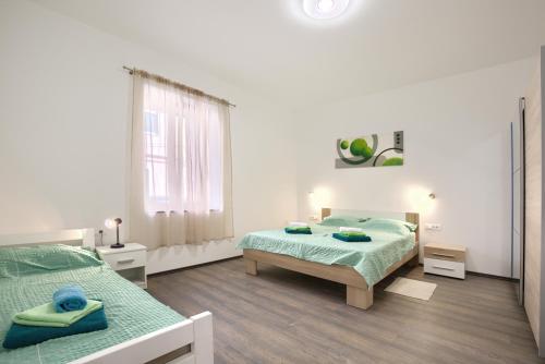 a white bedroom with two beds and a window at Amphitheater 3+2 modern apartment with terrace, WiFi, Netflix in Pula