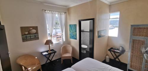 ケープタウンにあるCozy room in the Heart of Simon's Townの鏡、ベッド、椅子が備わる客室です。