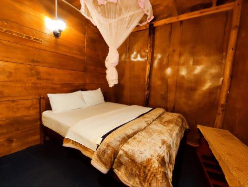 ein Schlafzimmer mit einem Bett in einer Holzwand in der Unterkunft Moon Plains Forest Log in Nuwara Eliya