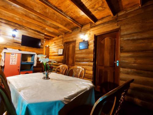 Un comedor con una mesa con un jarrón de flores encima. en Moon Plains Forest Log, en Nuwara Eliya