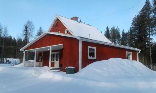 Un fienile rosso con un mucchio di neve intorno di Villa Polarktis a Överkalix