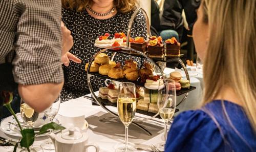 a woman sitting at a table with a tray of food at Home Hotel Grand Bodø in Bodø