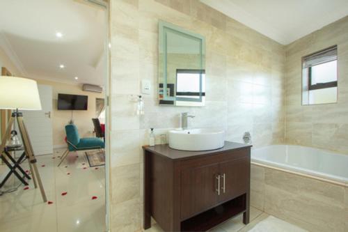 bagno con lavandino, vasca e specchio di Royal Hills Lodge and Spa a Thohoyandou
