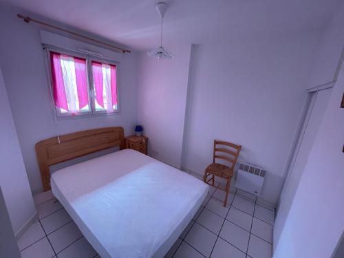 une petite chambre avec un lit et une chaise dans l'établissement Le Bruit Des Vagues, à Mimizan