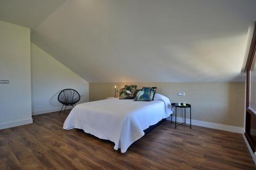 Un dormitorio con una cama blanca y suelos de madera. en GALIHOST - Casa Esclavi, en Cambados