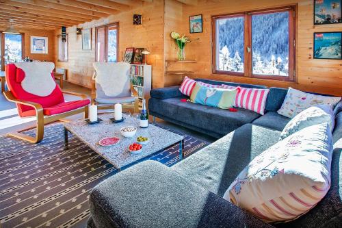 a living room with a blue couch and a red chair at Chalet Les Houlottes - OVO Network in Manigod