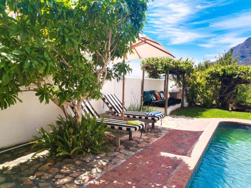 a swimming pool with two benches next to a house at InAweStays Holiday Homes in Cape Town