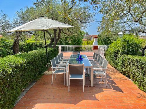 - une table avec des chaises et un parasol sur une terrasse en briques dans l'établissement Villa La Rodina, à Diano Marina