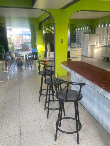 a group of tables and stools in a restaurant at Combate Green House in Cabo Rojo